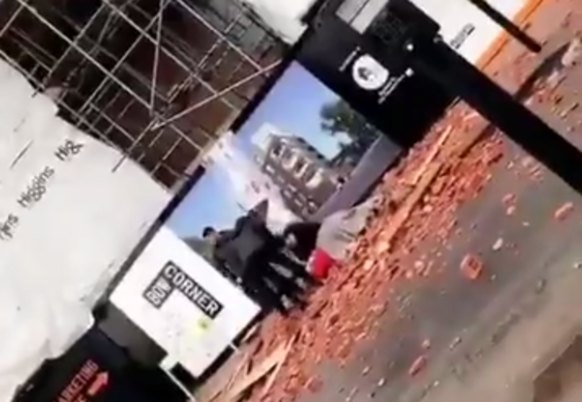 Shocked passers-by cover the prone woman hit by falling bricks