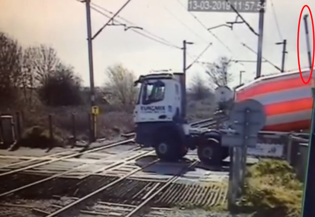  Level crossing camera view showing lorry stopped and about to start reversing manoeuvre. The crossing barrier (highlighted) has started to lower