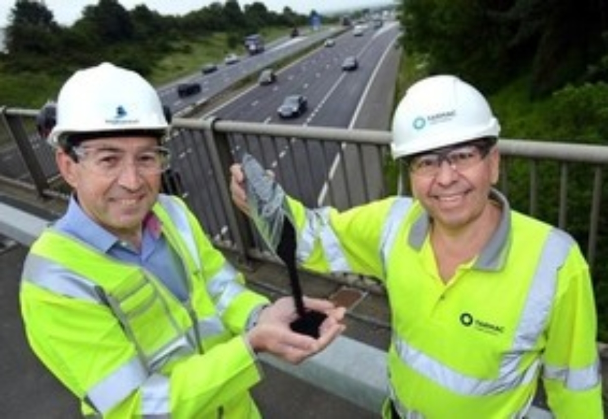 Martin Bolt, left, of Highways England and Paul Fleetham of Tarmac above the M1 in the East Midlands with some of the rubber granules being trialled in the road surface. 